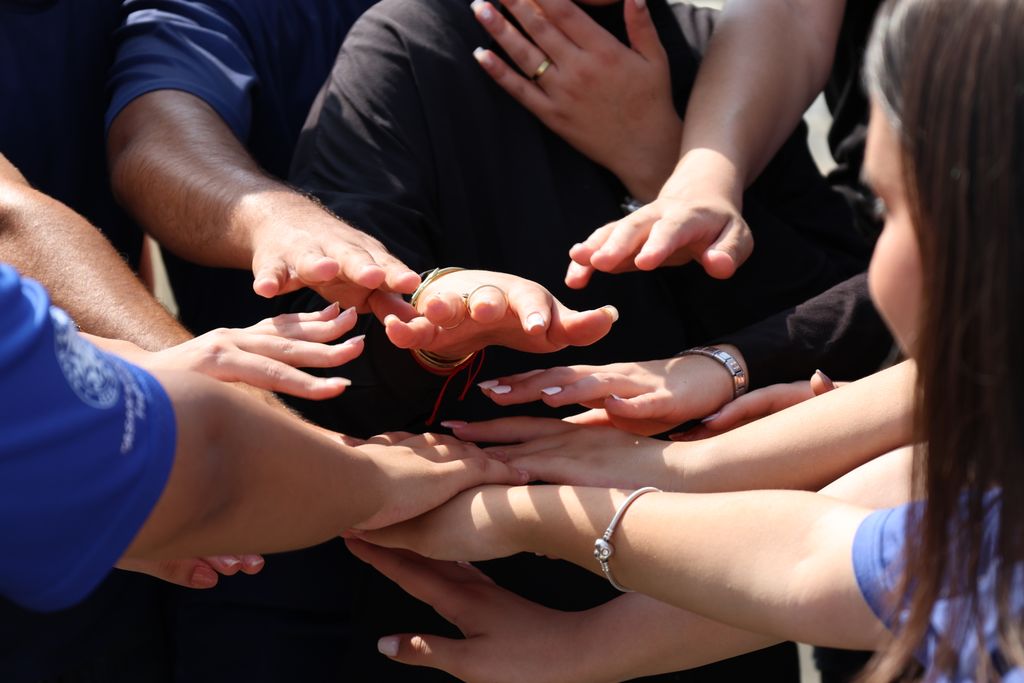 Hands coming together in a circle symbolizing unity, teamwork, and community spirit.